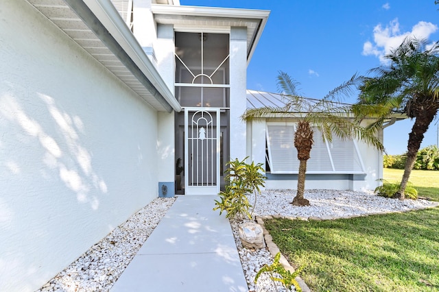 view of exterior entry with a lawn