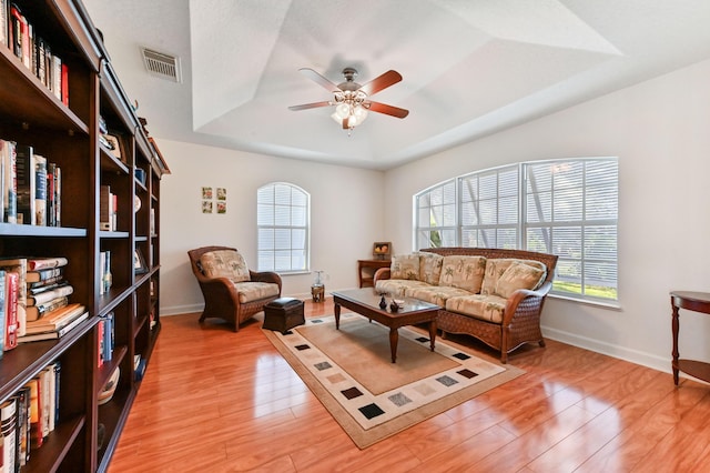 living area featuring a healthy amount of sunlight, a tray ceiling, ceiling fan, and light hardwood / wood-style floors