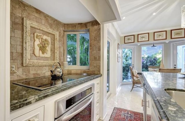 bar featuring electric cooktop, oven, plenty of natural light, and dark stone counters