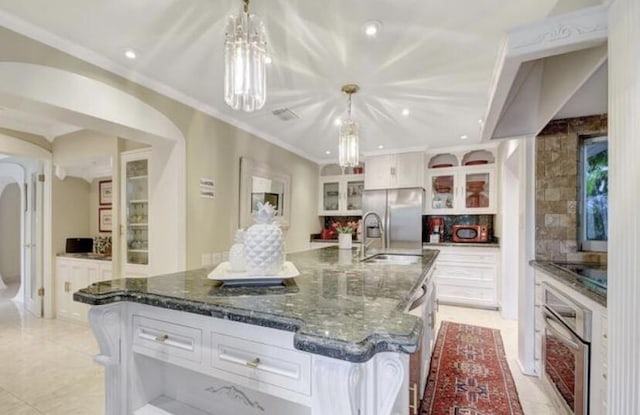 kitchen featuring appliances with stainless steel finishes, decorative light fixtures, white cabinetry, and a large island