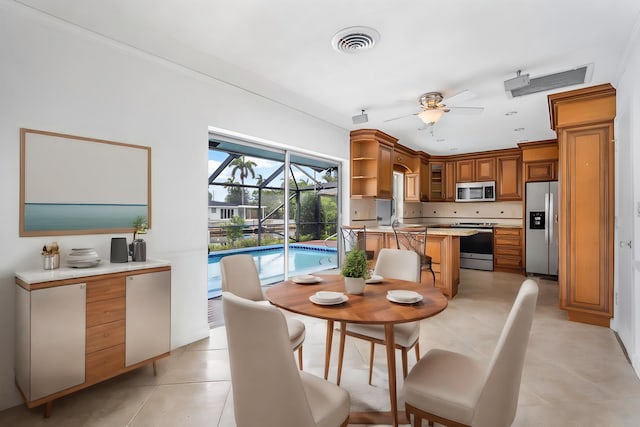 kitchen with ceiling fan, light tile patterned flooring, a kitchen bar, and appliances with stainless steel finishes