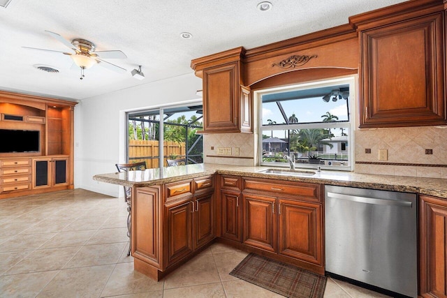 kitchen featuring kitchen peninsula, stainless steel dishwasher, ceiling fan, sink, and light tile patterned flooring