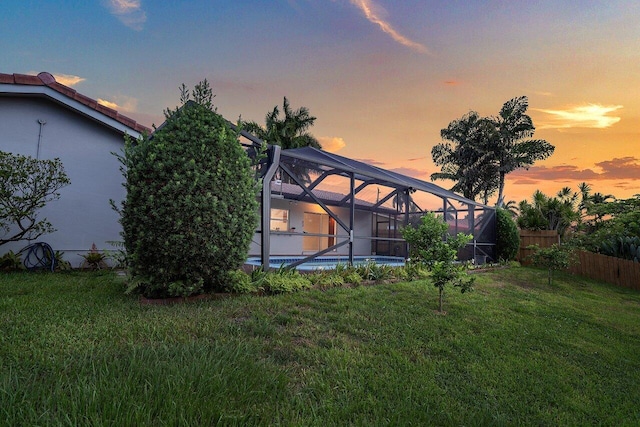 yard at dusk featuring a lanai