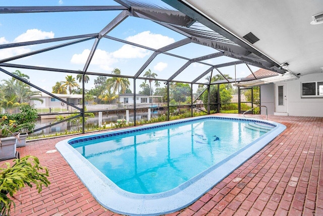 view of swimming pool featuring a lanai, a patio, and a water view