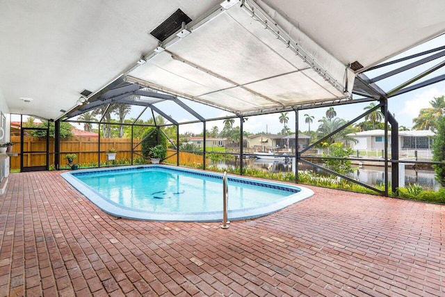 view of swimming pool with glass enclosure, a patio area, and a water view