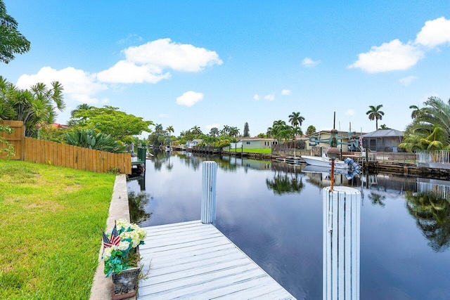 view of dock with a lawn and a water view