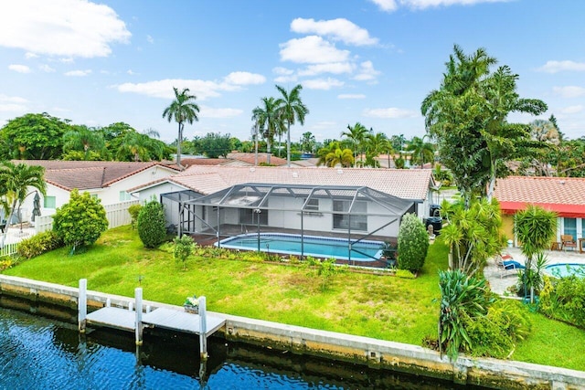 rear view of house with a water view, glass enclosure, and a lawn