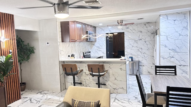 kitchen with tile walls, kitchen peninsula, a textured ceiling, and appliances with stainless steel finishes