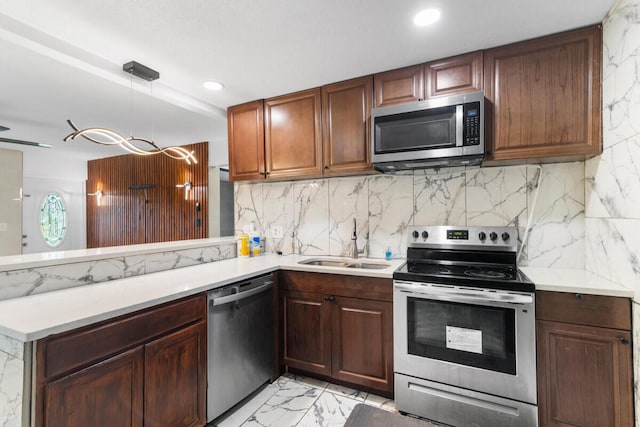 kitchen with sink, hanging light fixtures, tasteful backsplash, kitchen peninsula, and appliances with stainless steel finishes