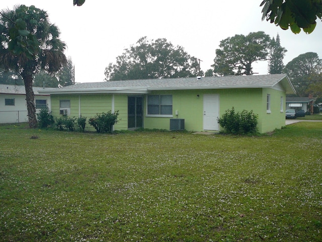 back of house featuring central air condition unit and a lawn