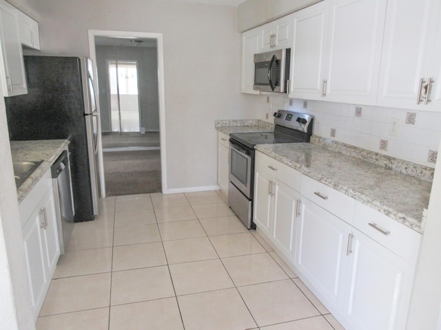 kitchen with light stone countertops, light tile patterned floors, white cabinetry, and appliances with stainless steel finishes