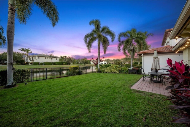 yard at dusk with a patio and a water view