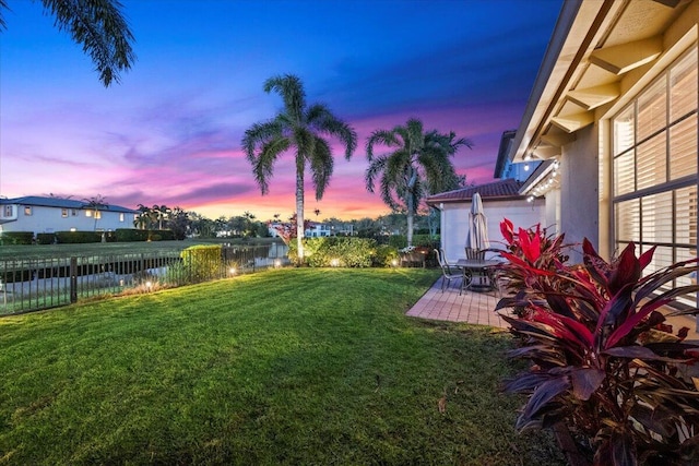 yard at dusk featuring a patio area and a water view