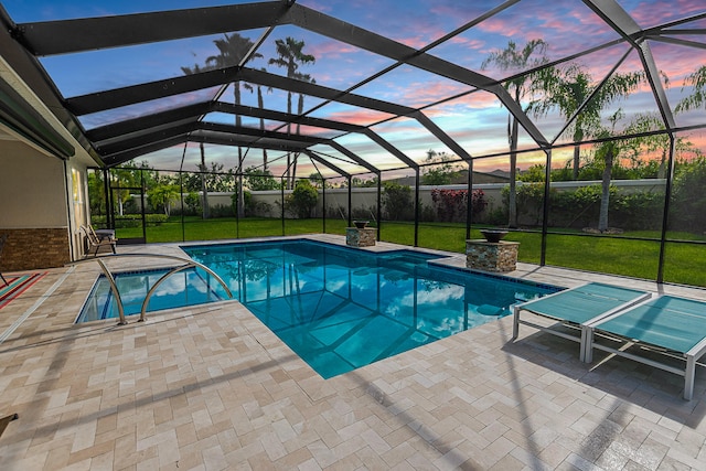 pool at dusk featuring a patio, glass enclosure, and a lawn