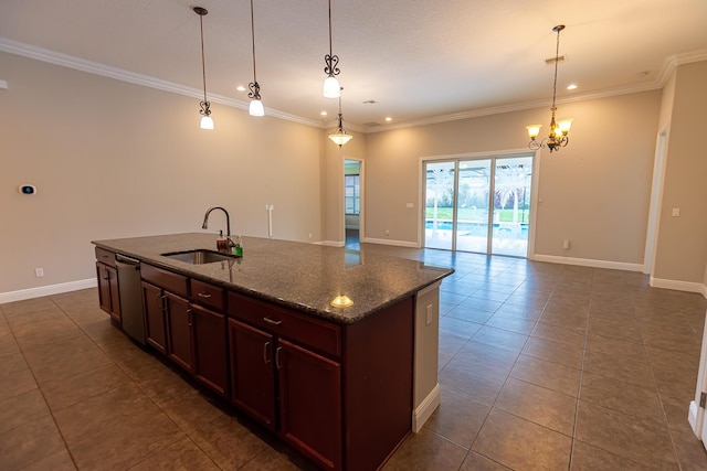 kitchen with an island with sink, sink, dark tile patterned flooring, dark stone counters, and hanging light fixtures