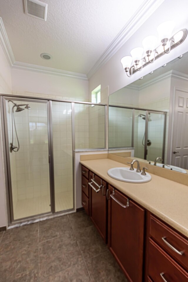 bathroom with ornamental molding, vanity, an enclosed shower, and a textured ceiling