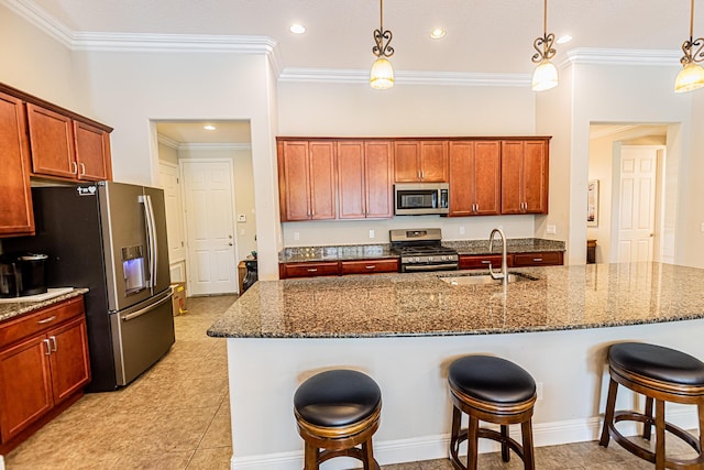 kitchen with a kitchen bar, stainless steel appliances, sink, decorative light fixtures, and a center island with sink