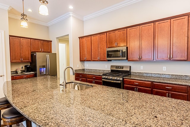 kitchen with sink, hanging light fixtures, ornamental molding, appliances with stainless steel finishes, and a kitchen breakfast bar