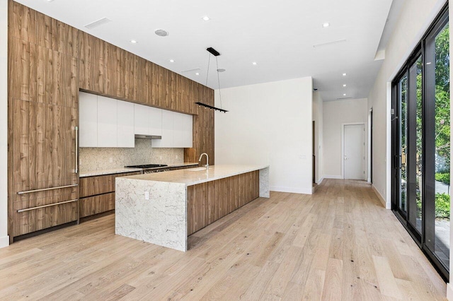 kitchen with modern cabinets, a sink, light wood-style floors, black cooktop, and white cabinetry