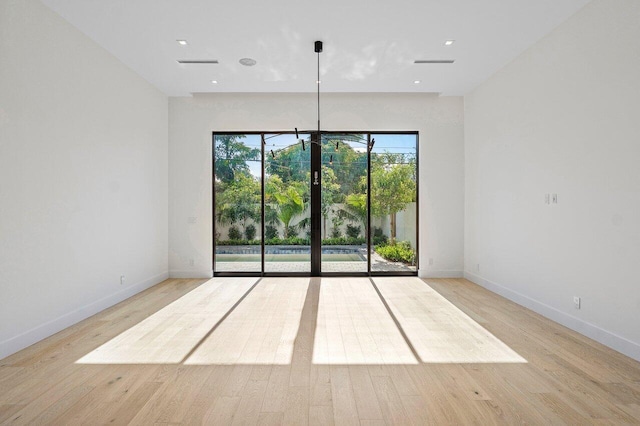 unfurnished room featuring baseboards, light wood-style flooring, and visible vents