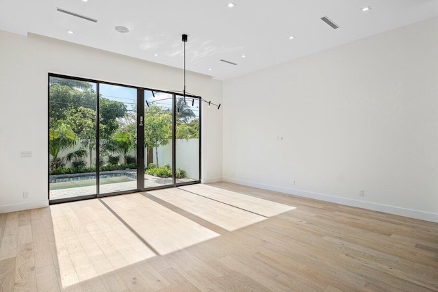 spare room with baseboards, visible vents, and light wood-type flooring
