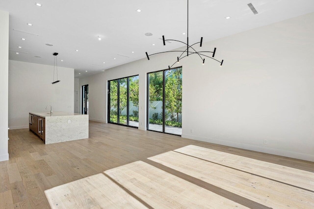 unfurnished living room featuring baseboards, a chandelier, and visible vents