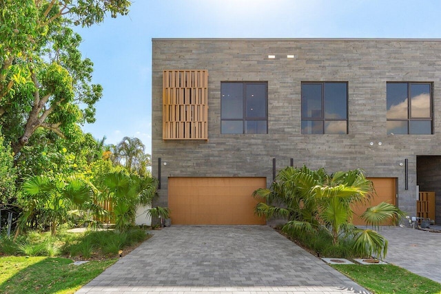 modern home featuring an attached garage and decorative driveway