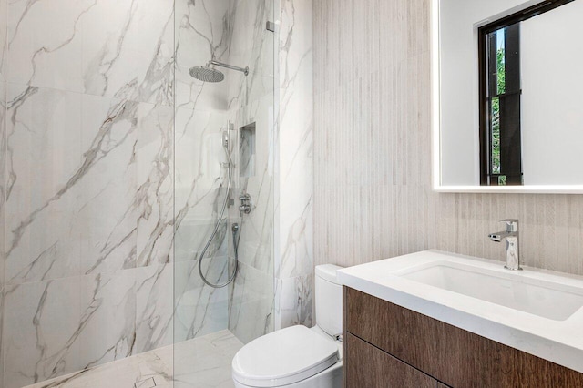 bathroom featuring toilet, tile walls, a marble finish shower, and vanity