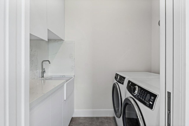 laundry area with washing machine and clothes dryer, cabinet space, a sink, baseboards, and wet bar