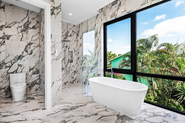 full bath featuring a freestanding bath, stone wall, toilet, marble finish floor, and a marble finish shower