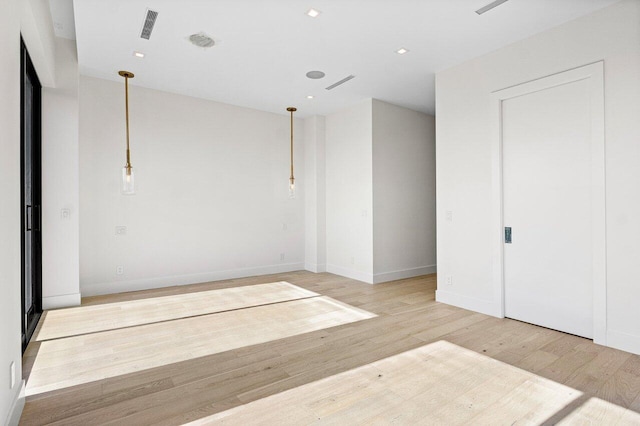 unfurnished room featuring baseboards, visible vents, and light wood-type flooring