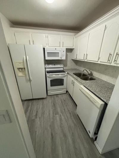 kitchen with white appliances, light hardwood / wood-style floors, white cabinetry, and sink