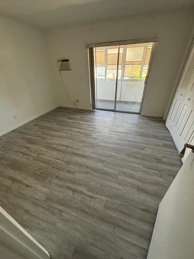 empty room with dark hardwood / wood-style flooring and an AC wall unit