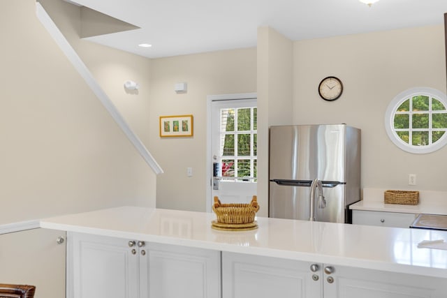 kitchen with stainless steel fridge and white cabinetry