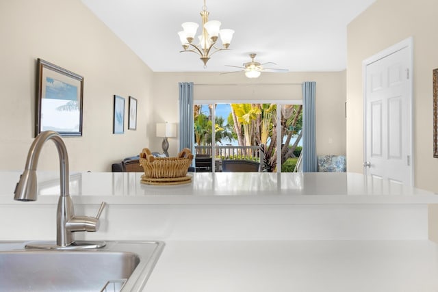 interior details featuring ceiling fan with notable chandelier, kitchen peninsula, pendant lighting, and sink