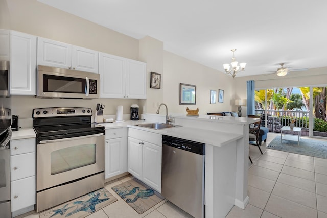 kitchen with stainless steel appliances, kitchen peninsula, light tile patterned floors, sink, and white cabinetry