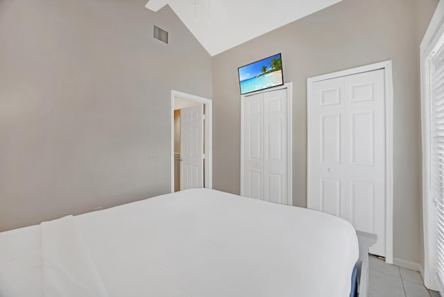 bedroom featuring ceiling fan, light tile patterned flooring, and lofted ceiling