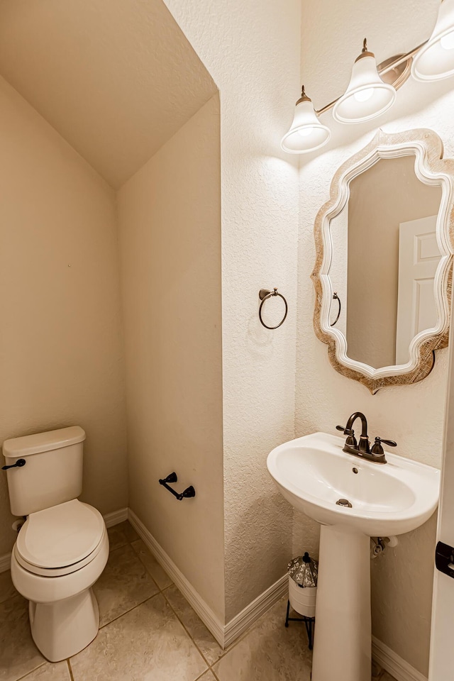 bathroom featuring tile patterned flooring, lofted ceiling, and toilet