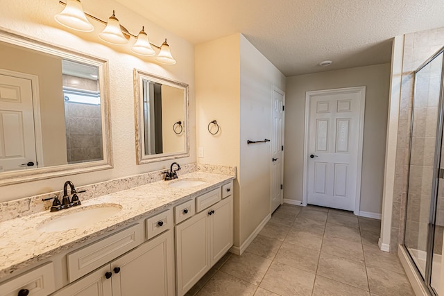 bathroom featuring an enclosed shower, vanity, tile patterned floors, and a textured ceiling