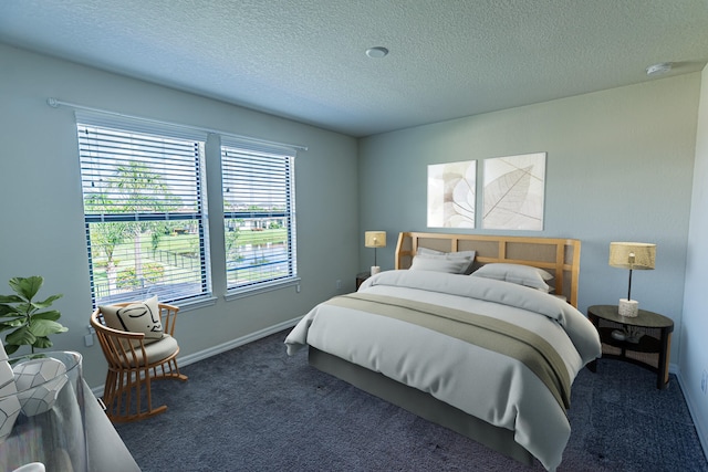 bedroom featuring a textured ceiling and dark carpet