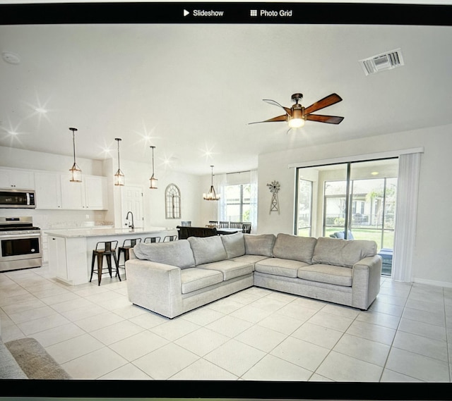 tiled living room featuring ceiling fan with notable chandelier