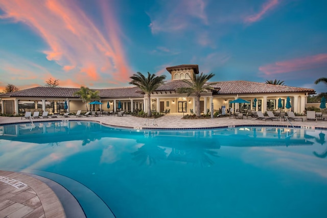 pool at dusk featuring a patio area