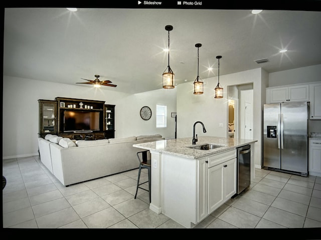 kitchen featuring pendant lighting, white cabinetry, sink, stainless steel appliances, and a center island with sink