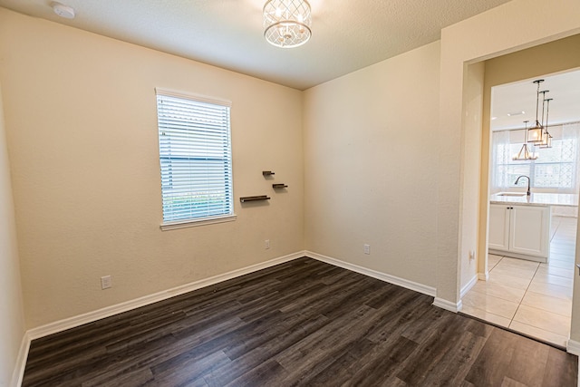 spare room featuring wood-type flooring, sink, and a textured ceiling