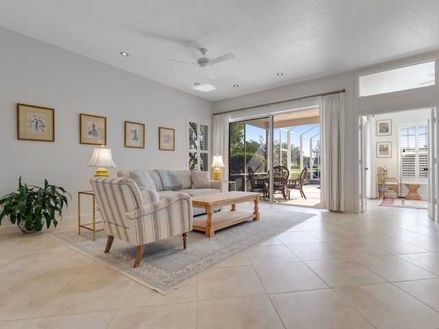 living room with ceiling fan, light tile patterned flooring, and a textured ceiling