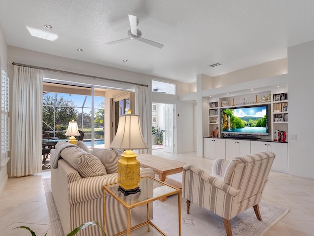 living room featuring ceiling fan, built in features, a textured ceiling, and light tile patterned floors