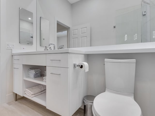 bathroom featuring walk in shower, hardwood / wood-style floors, vanity, and toilet