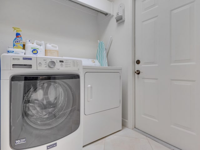 clothes washing area with washer and clothes dryer and light tile patterned flooring