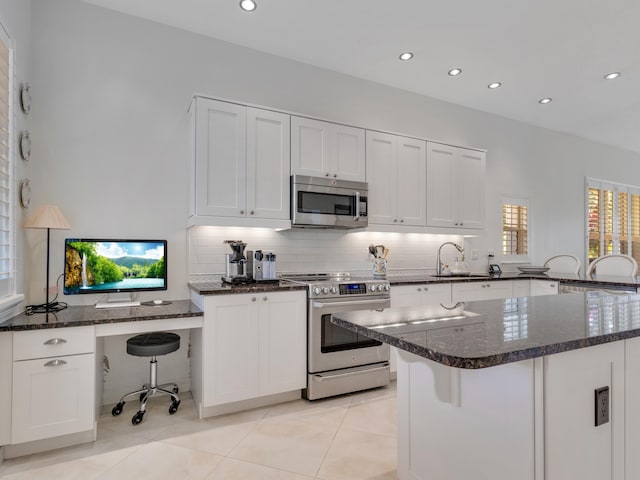 kitchen featuring a breakfast bar, dark stone countertops, white cabinetry, and stainless steel appliances