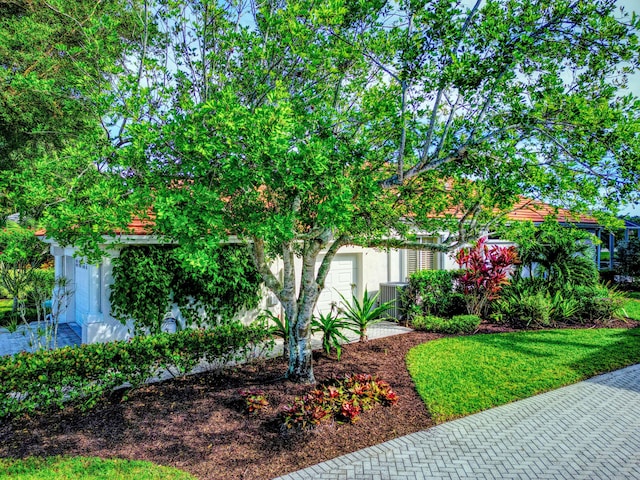 exterior space featuring a front lawn, a garage, and cooling unit